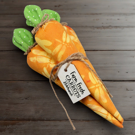 Plush carrot bundle with green top on a wooden surface, featuring a 'Farm Fresh Carrots' tag.