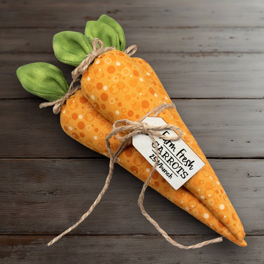 Plush fabric carrots with a tag on a wooden surface