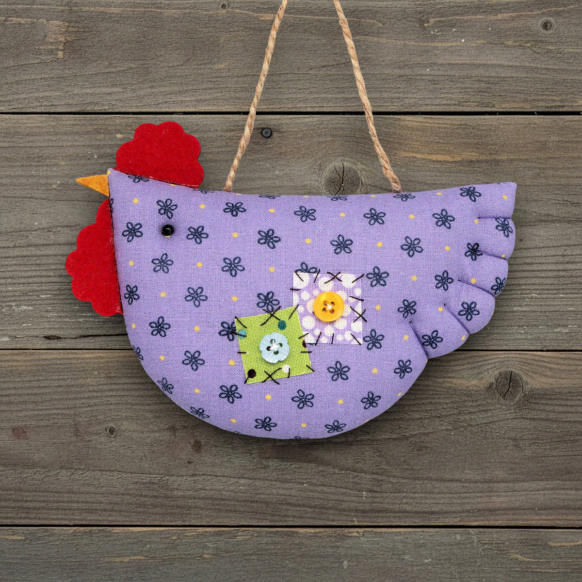 Decorative chicken ornament with purple body and red comb on a wooden background