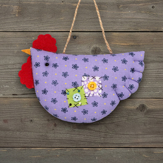 Decorative chicken ornament with purple body and red comb on a wooden background