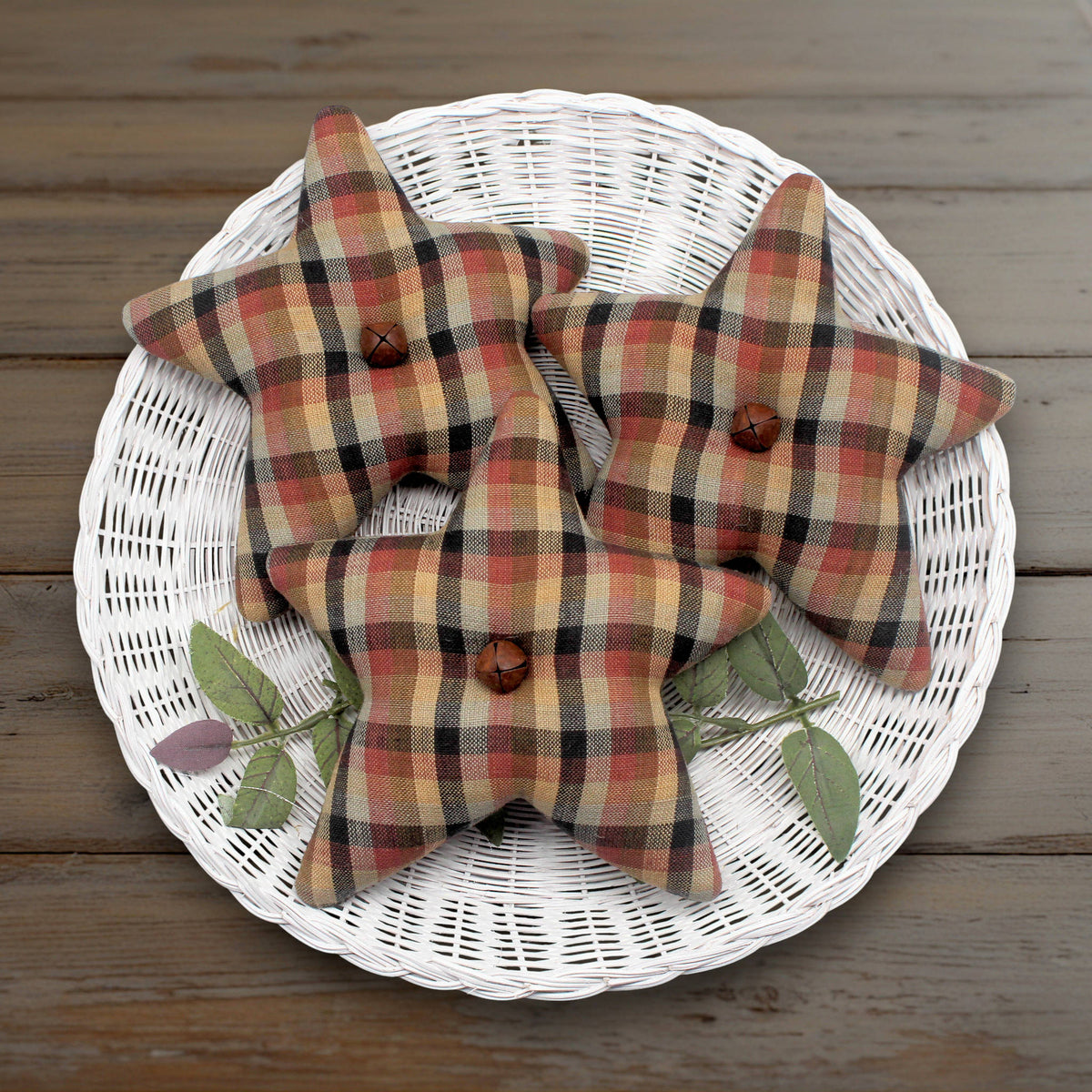 Set of three homespun stars made from brown, rust and tan fabric with rusty bells in the centers