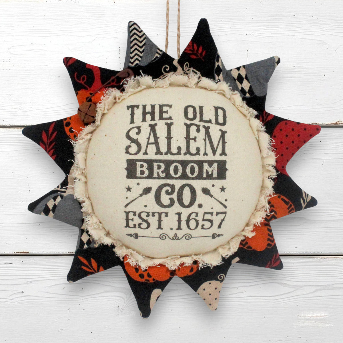 A circular fabric sunflower ornament wall hanging with the text 'THE OLD SALEM BROOM CO. EST.