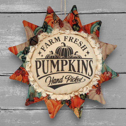 A fabric sunflower ornament with a rustic autumn design. The center features a beige circle with a frayed edge, printed with the text 'FARM FRESH PUMPKINS Hand Picked' and an illustration of three pumpkins.
