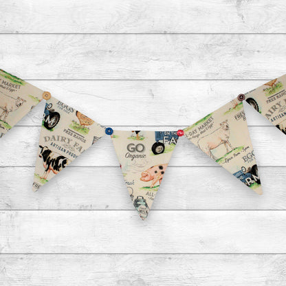 A bunting banner with triangular flags printed with vintage-style dairy farm illustrations and text, hung on a white wood plank background.