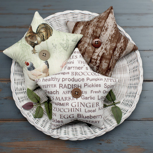 Decorative fabric stars with farmhouse fabric designs on a wicker basket against a wooden background