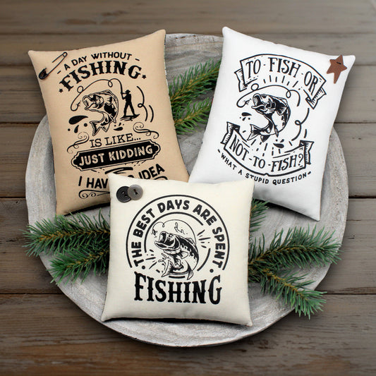 Three fishing-themed pillows on a wooden surface with greenery.