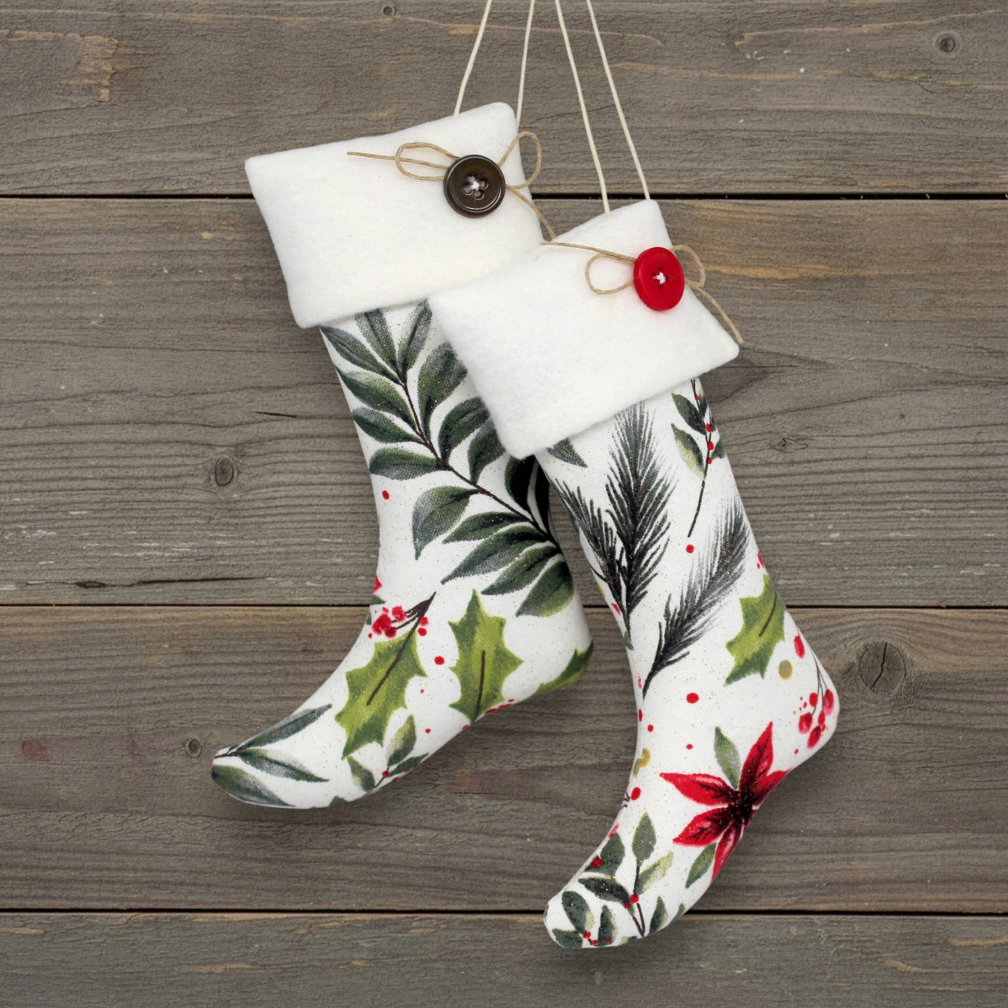 Decorative Christmas stocking ornaments with floral poinsettia and greenery patterns hanging on a wooden surface.