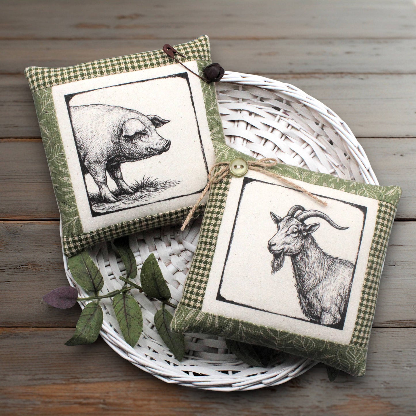 Two decorative square fabric pillows with gingham trim and black-and-white animal illustrations, displayed on a white woven tray over a rustic wooden surface.