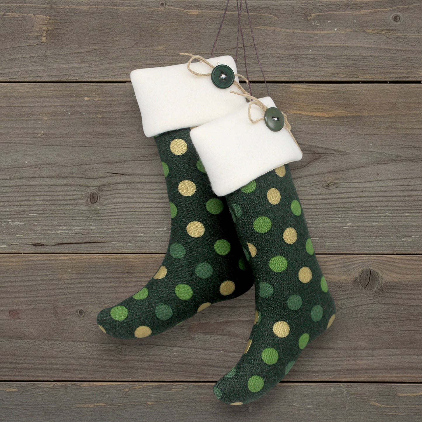 Pair of handmade Christmas stocking ornaments with gold and green polka dots on a dark green background