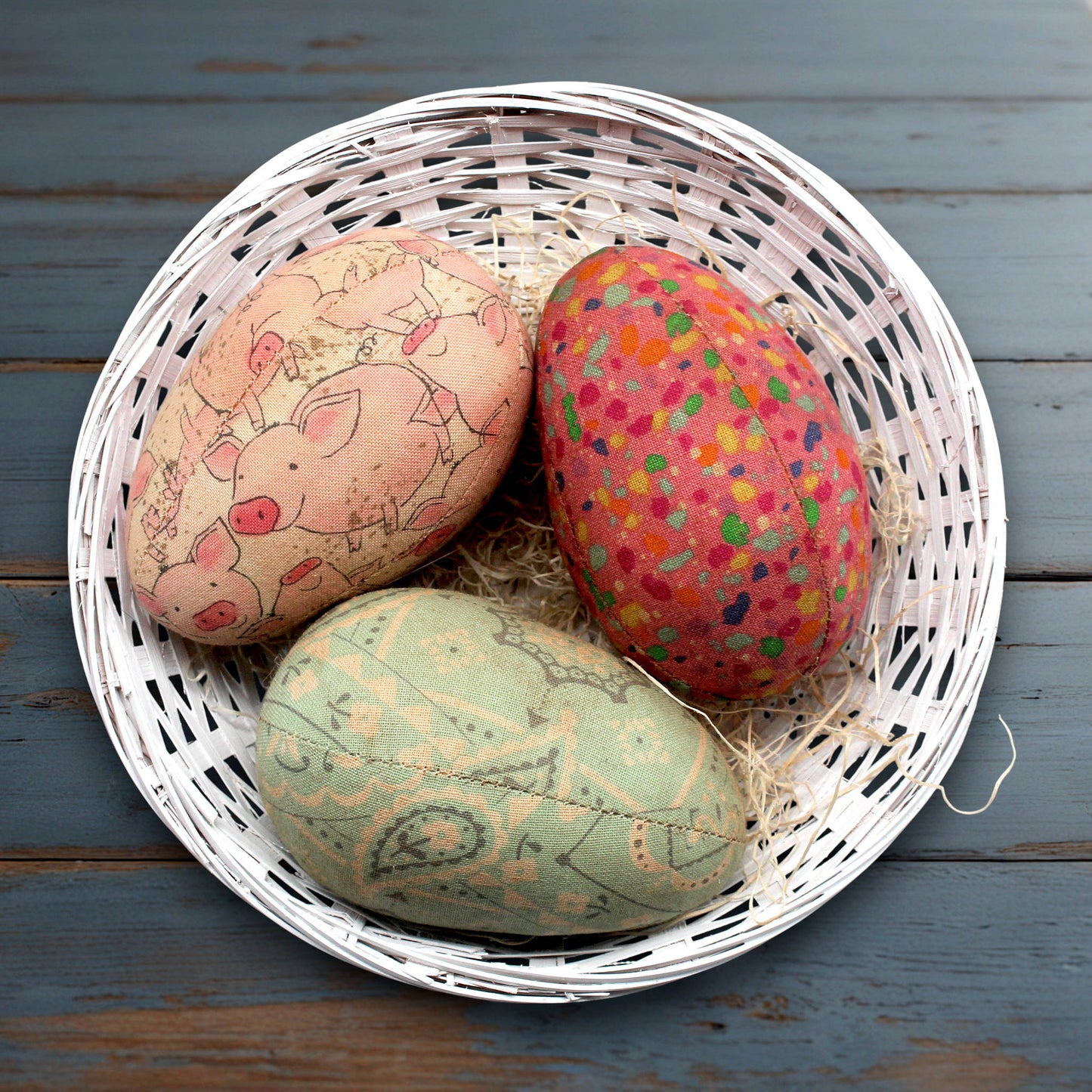 Decorative eggs with animal prints in a white basket on a wooden surface