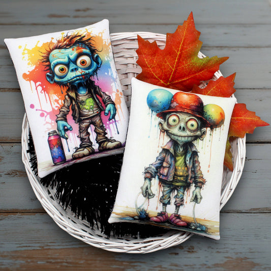 Two colorful pillows with cartoonish funny zombie designs on a wooden surface with autumn leaves.