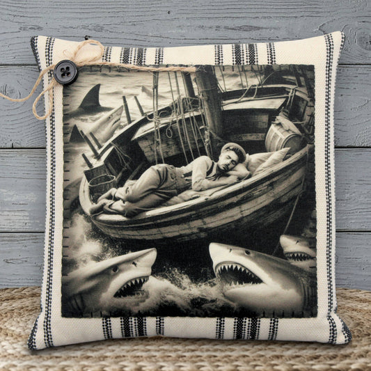 Pillow with a black and white illustration of a man in a boat surrounded by sharks.