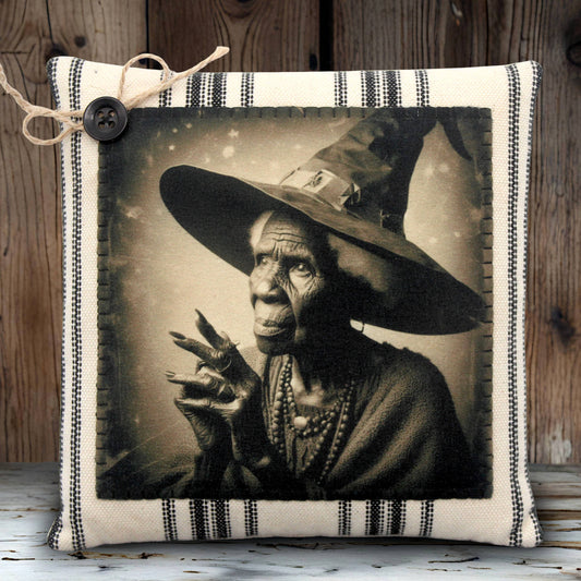 Decorative pillow with a vintage-style portrait of an elderly woman witch wearing a wide-brimmed hat on a wooden background.