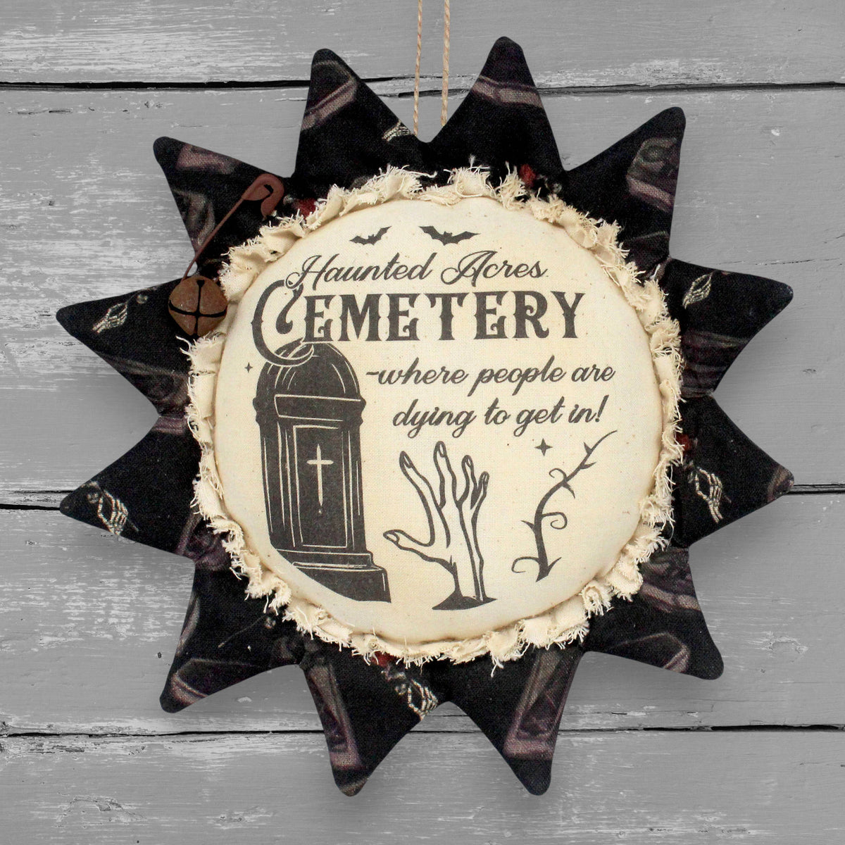Fabric sunflower ornament for Halloween featuring a printed center that advertises for Haunted Acres Cemetery where people are dying to get in.