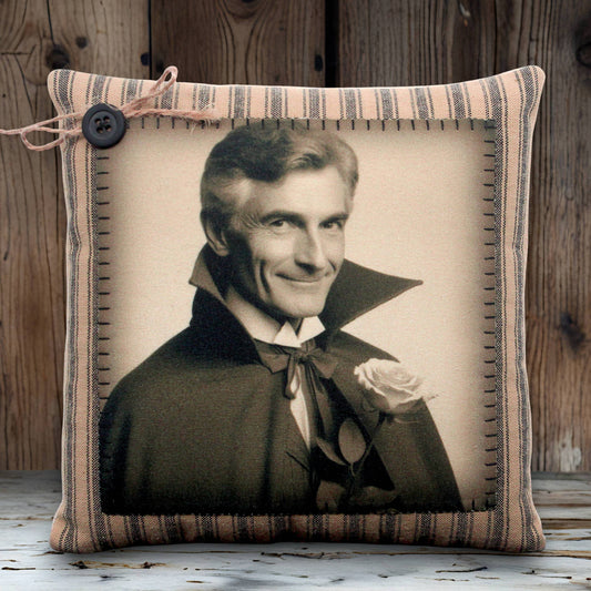 Pillow with a vintage-style portrait of a handsome vampire in a dark coat and cape holding a rose, framed by striped fabric.