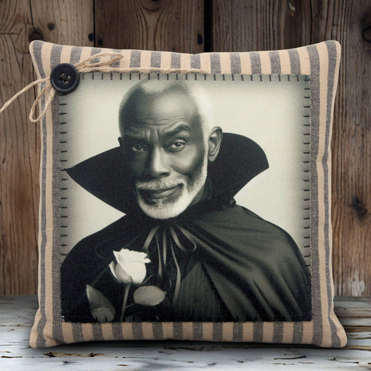 Pillow with a black and white portrait of a handsome vampire in a cape holding a rose, framed by striped fabric.
