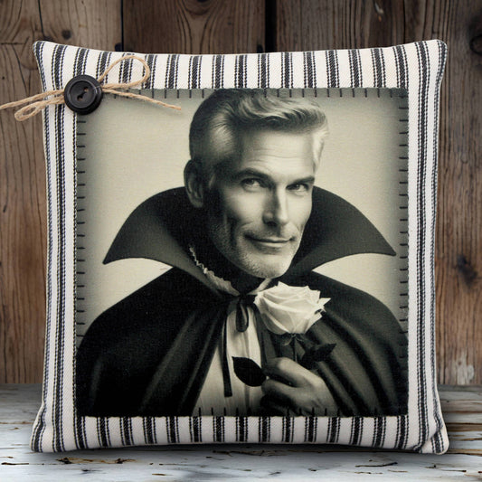 Pillow with a black and white print of a handsome vampire in a cape holding a rose, on a striped pillow cover.
