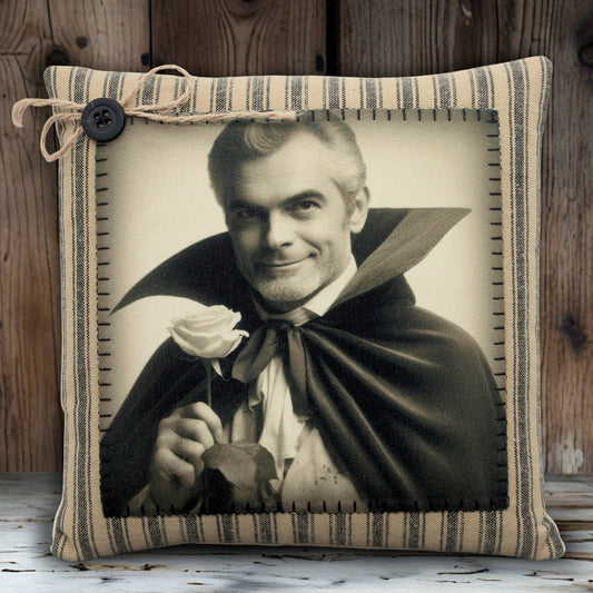 Pillow with a vintage-style print of a handsome vampire in a cape holding a rose, framed by striped fabric.