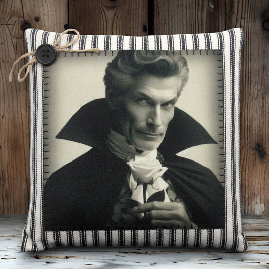 Decorative pillow with a black and white portrait of a handsome vampire in a cape holding a rose, framed by a striped border.