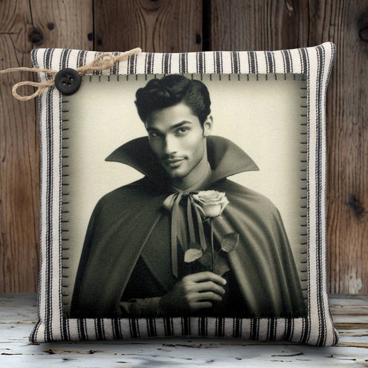 Decorative pillow with a black and white print of a handsome young vampire in a cape holding a rose, on a striped fabric background.