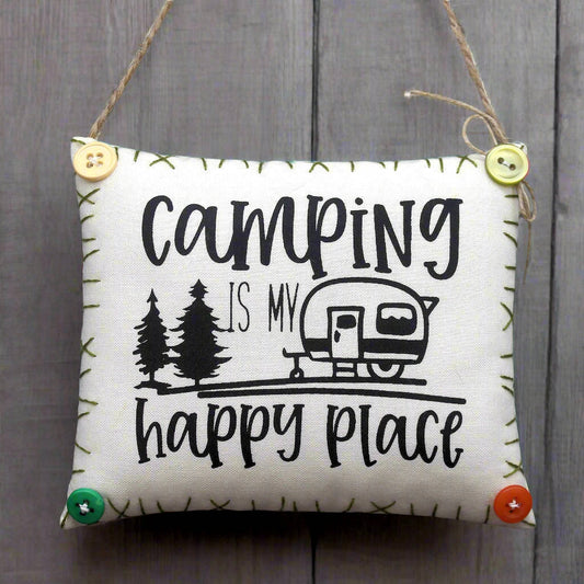 Decorative sign with 'Camping is my happy place' text and camper illustration on a wooden background.