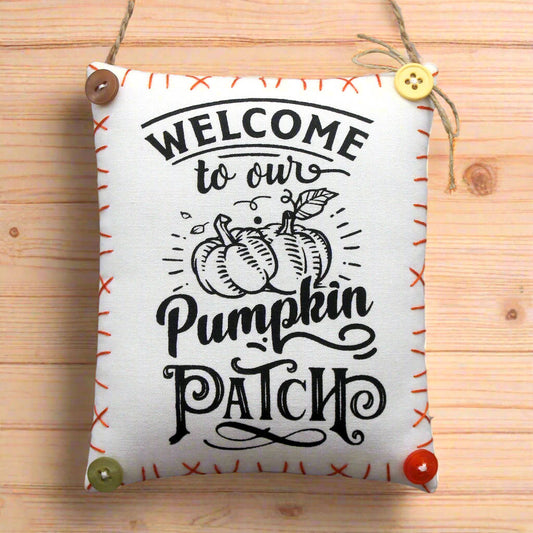 Decorative sign with 'Welcome to our Pumpkin Patch' text on a wooden background