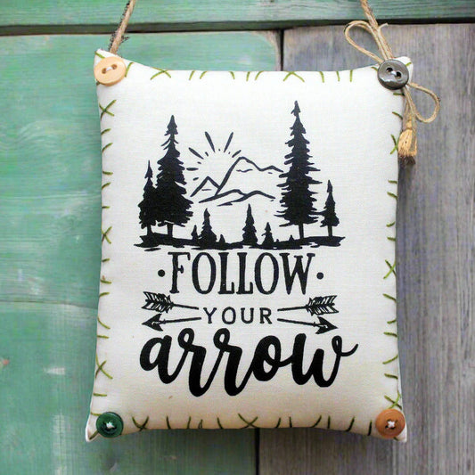 Mini pillow fabric sign that reads "follow your arrow"