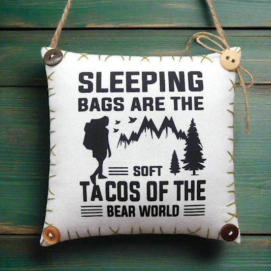 Decorative pillow with humorous camping quote on a wooden background