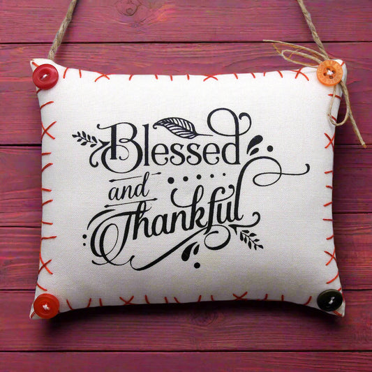 Decorative pillow with 'Blessed and Thankful' text on a wooden background