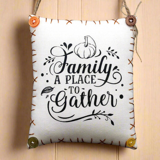 Decorative pillow with 'Family A Place To Gather' text and pumpkin design on a wooden background