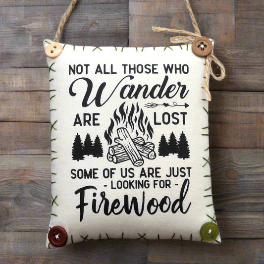 Decorative sign with camping-themed text and illustrations on a wooden background