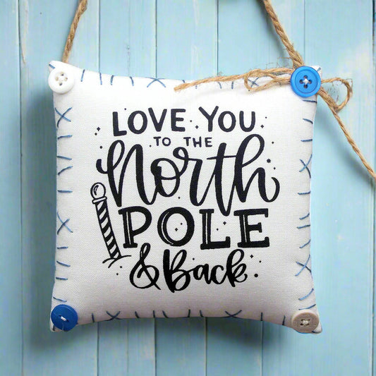 Decorative pillow with 'Love you to the North Pole & Back' text on a blue wooden background