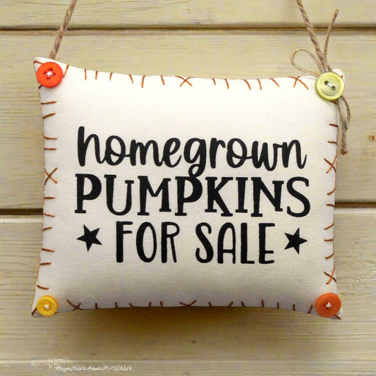 Fabric sign with 'homegrown pumpkins for sale' text on a wooden background