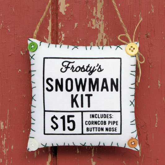Fabric ornament labeled 'Frosty's Snowman Kit' with price and features on a gray background