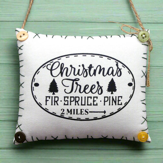 Decorative pillow with Christmas tree text on a green wooden background