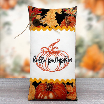 Elongated mini pillow tuck or bowl filler with an embroidered center panel with a pumpkin and text 'hello pumpkin.'  The center panel is trimmed with rick rack and colorful fall fabric.