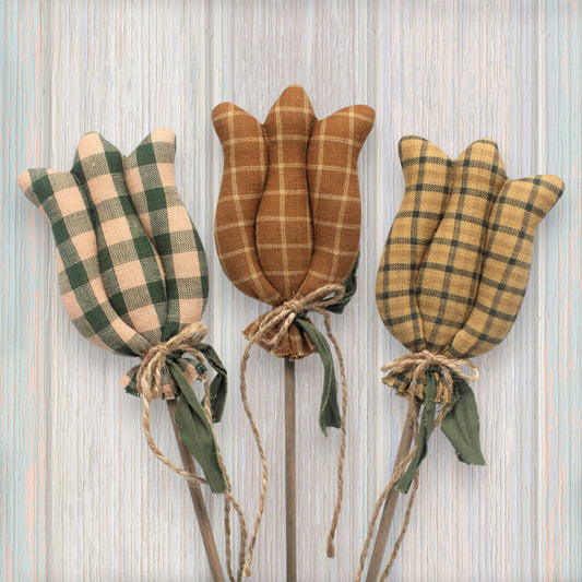 Three plaid tulip decorations on sticks against a striped background