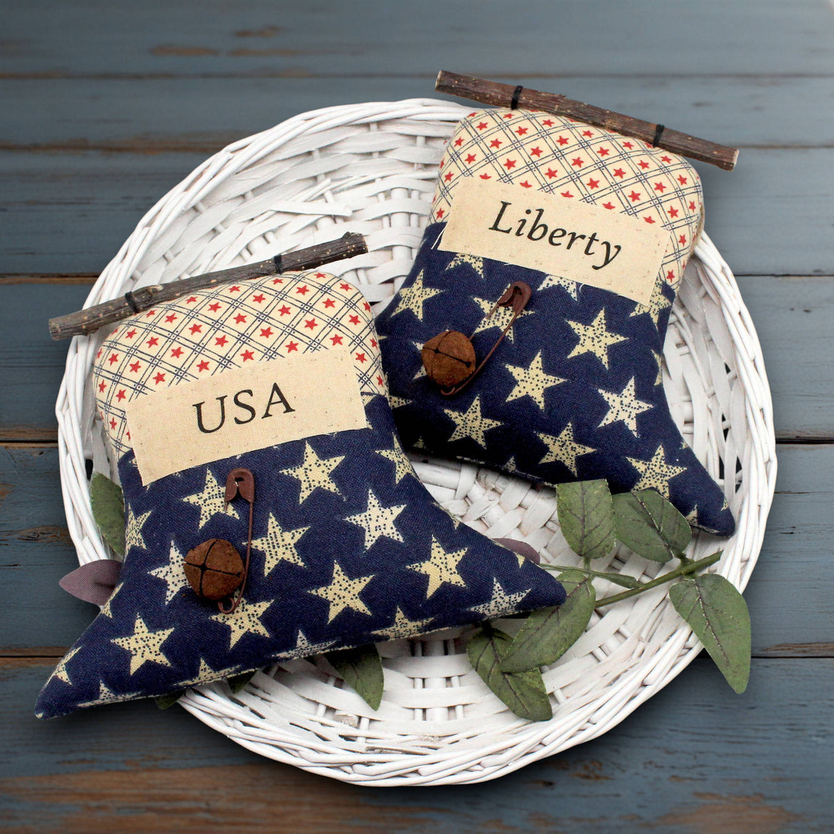 Set of two primitive liberty bell ornaments with labels that read USA and Liberty, decorated with rusty bells and safety pins