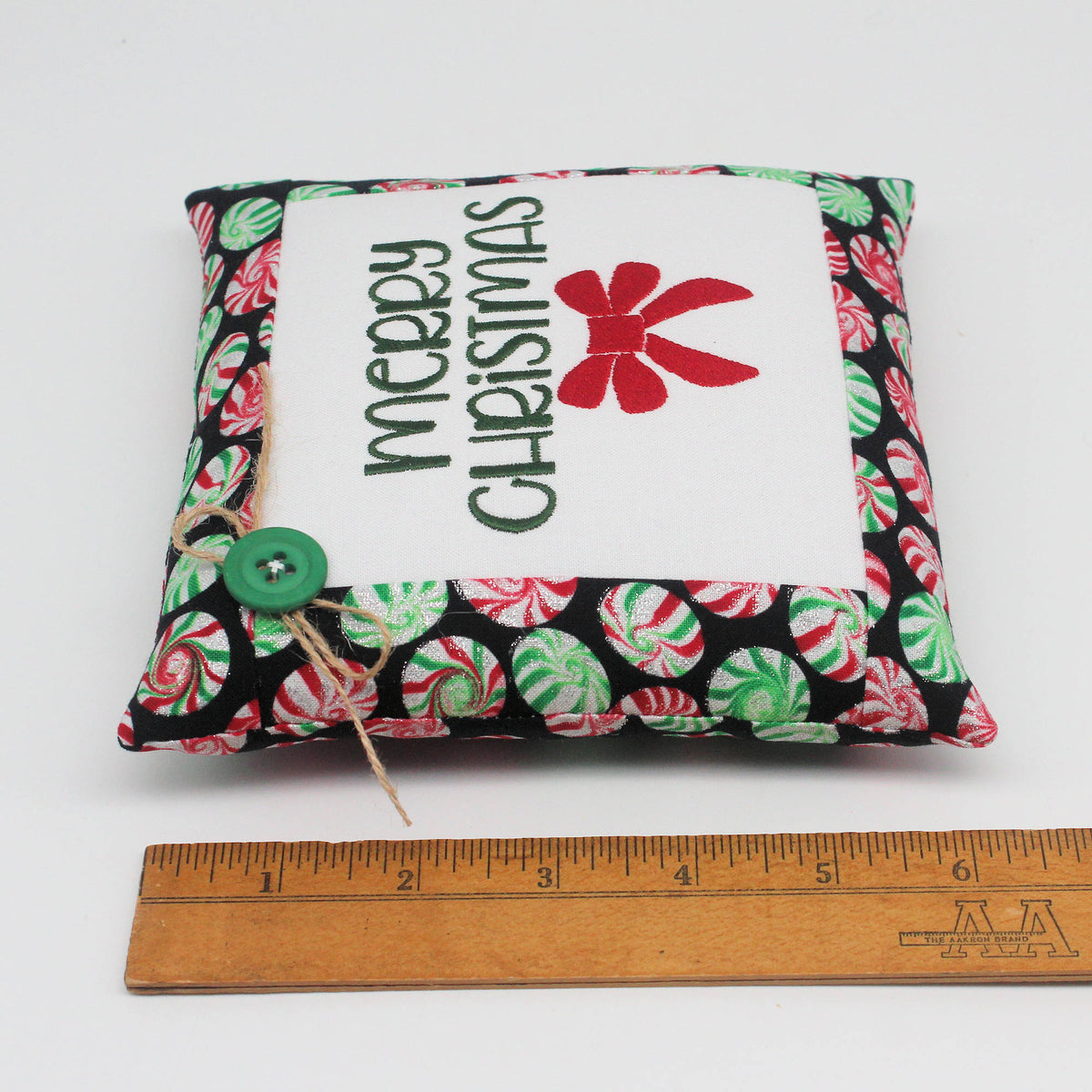Small embroidered pillow embroidered with the words "Merry Christmas" and a red bow