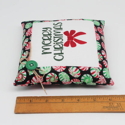 Small embroidered pillow embroidered with the words "Merry Christmas" and a red bow