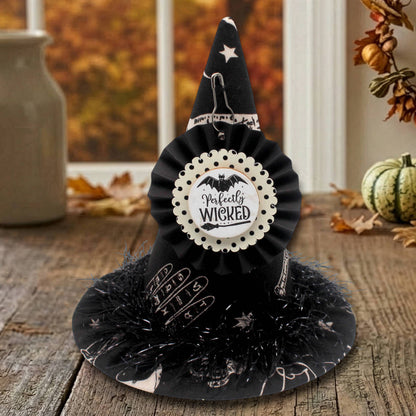 Miniature witch hat in black fabric with a tag that reads 'perfectly wicked'