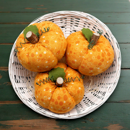 Set of three small fabric pumpkins with a polka dot print design in a white wicker basket