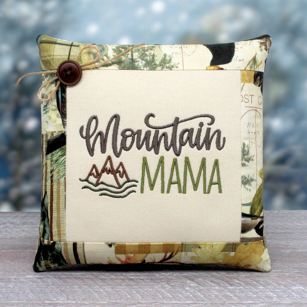 Small pillow tuck or bowl filler embroidered with 'mountain mama' and trimmed with a fabric with a rustic woodsy design