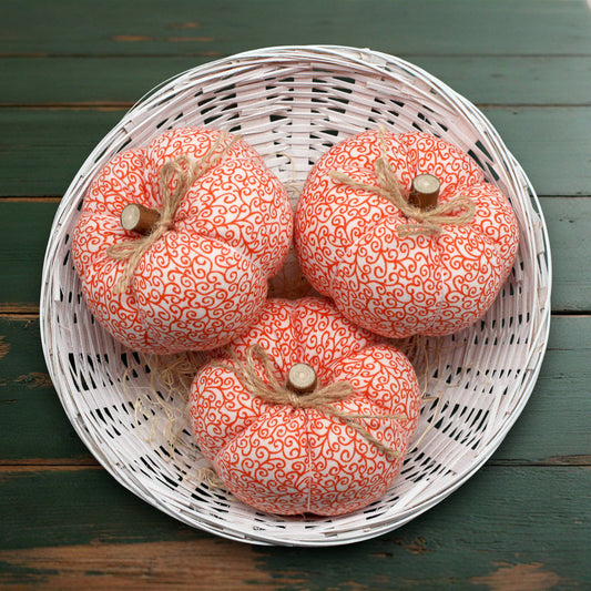 Decorative pumpkins with orange patterns in a white basket on a wooden surface