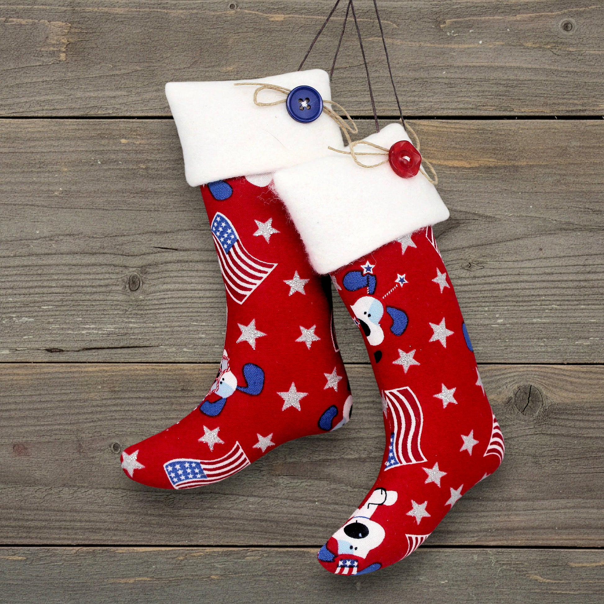 Pair of Christmas stocking ornaments with patriotic dogs, American flags and silver stars on a red fabric background
