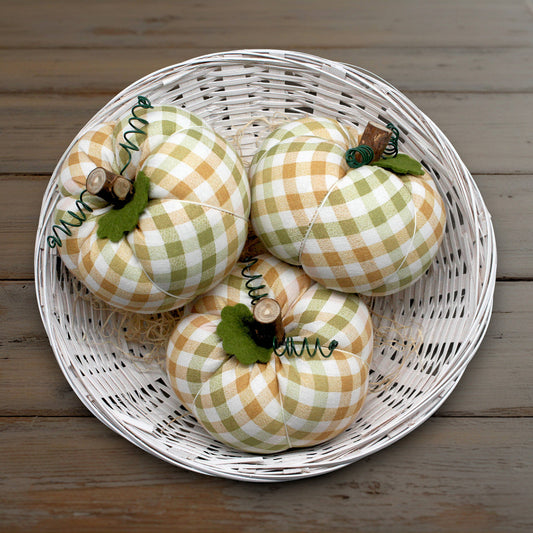 Decorative checkered pumpkins in a white wicker basket on a wooden surface
