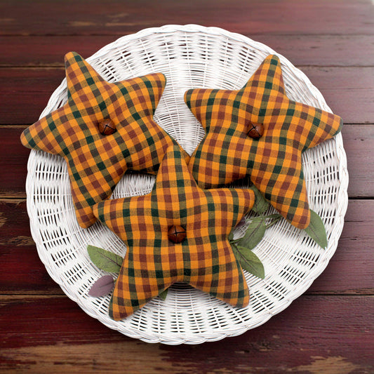 Set of three stars made from orange, green and purple homespun fabric with rusty bells in their centers