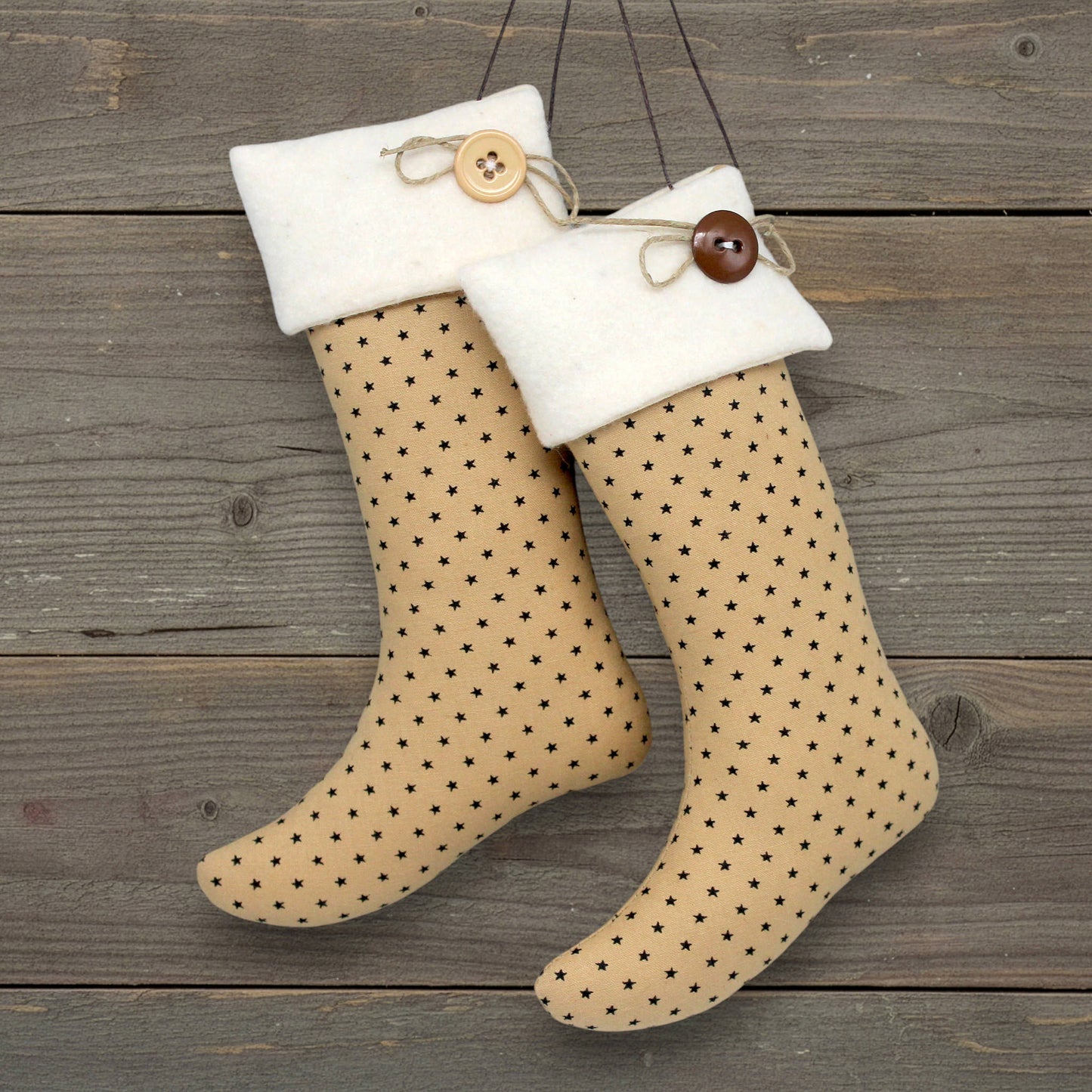 Pair of Christmas stocking ornaments with tiny black stars on tan fabric with fleece cuffs