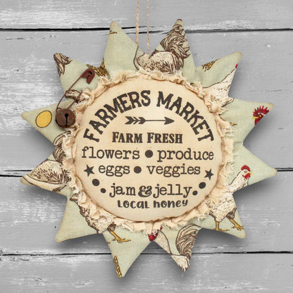 Primitive distressed handmade fabric sunflower ornament with a printed center that advertises for a local farmers market.