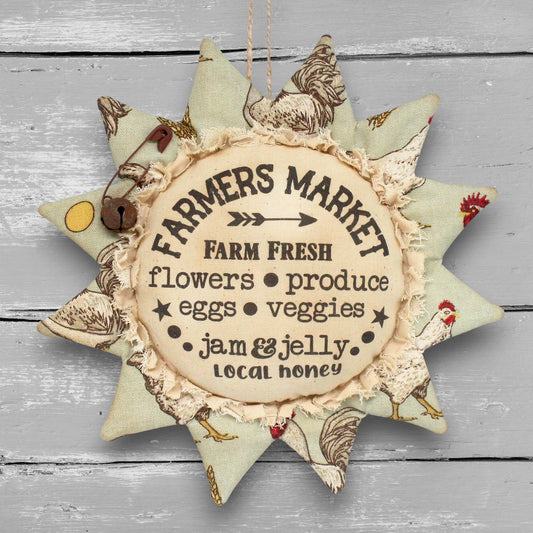 Primitive distressed handmade fabric sunflower ornament with a printed center that advertises for a local farmers market.